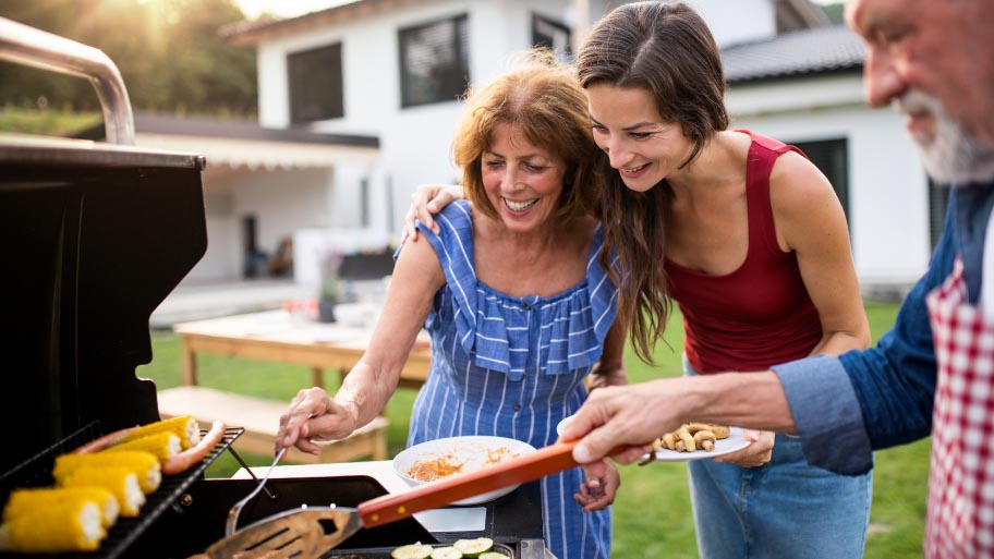 Family Enjoying Cooking at Spring Barbecue Garden Party Family Enjoying Cooking at Spring Barbecue Garden Party